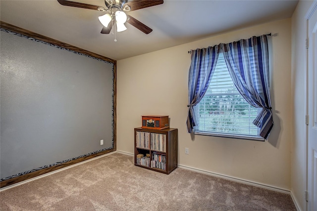 carpeted empty room featuring baseboards and a ceiling fan