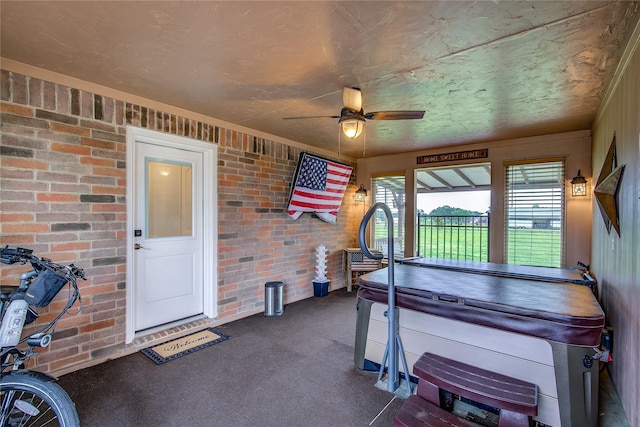 exterior space featuring brick wall, ceiling fan, and dark colored carpet