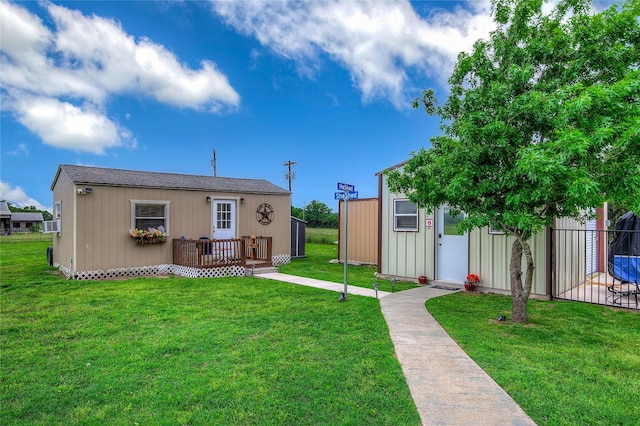 view of front of property featuring a wooden deck, an outdoor structure, and a front yard