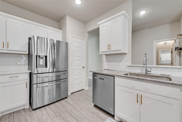 kitchen featuring stainless steel appliances, white cabinets, a sink, and decorative backsplash