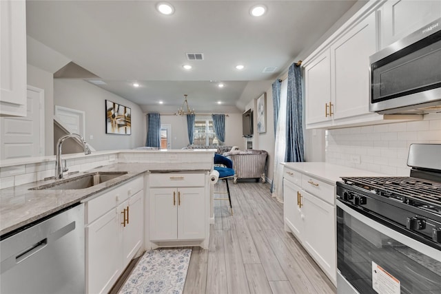 kitchen featuring white cabinetry, visible vents, a sink, stainless steel appliances, and decorative backsplash