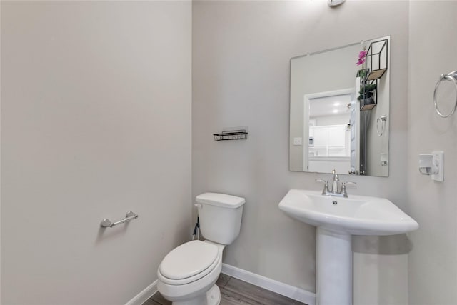bathroom featuring toilet, wood finished floors, a sink, and baseboards