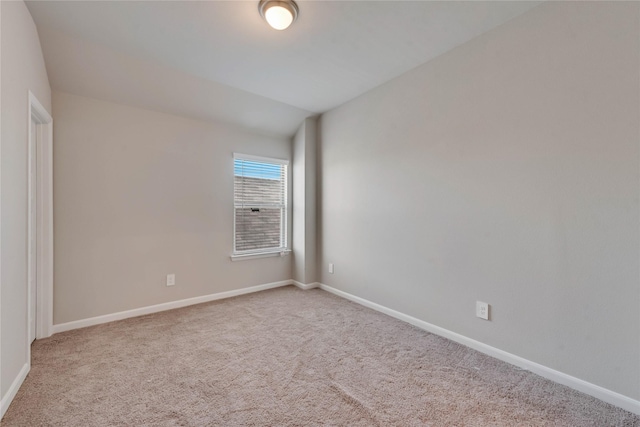 spare room featuring baseboards, carpet flooring, and lofted ceiling