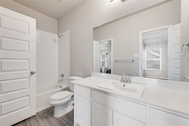 bathroom featuring toilet, wood finished floors, vanity, and shower / bathing tub combination