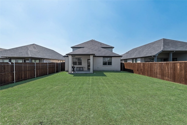 back of house with brick siding, a fenced backyard, a patio, and a lawn