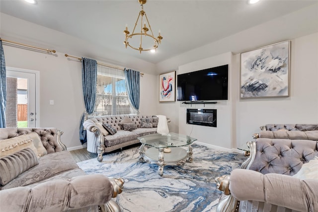 living area featuring baseboards, a notable chandelier, recessed lighting, wood finished floors, and a glass covered fireplace