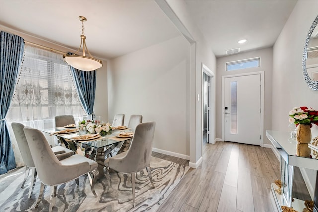 dining room featuring light wood-style flooring, baseboards, and visible vents