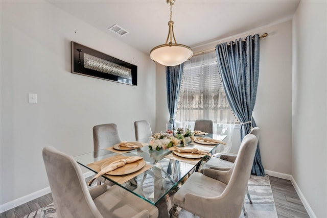 dining space featuring wood finished floors, baseboards, and visible vents