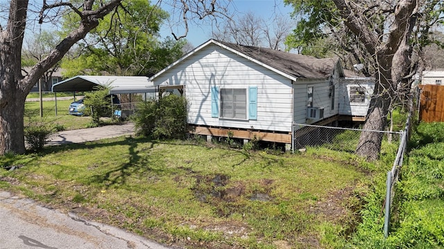 view of side of home featuring fence, a detached carport, and a lawn
