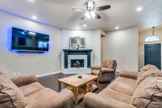 living room with visible vents, baseboards, ceiling fan, a fireplace, and dark wood finished floors
