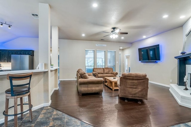 living room with dark wood-type flooring, visible vents, and a ceiling fan