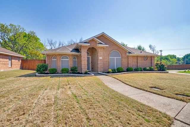 view of front facade with a front yard, brick siding, and fence