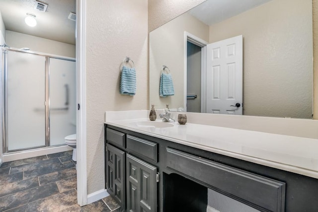 bathroom with a textured wall, toilet, vanity, and baseboards