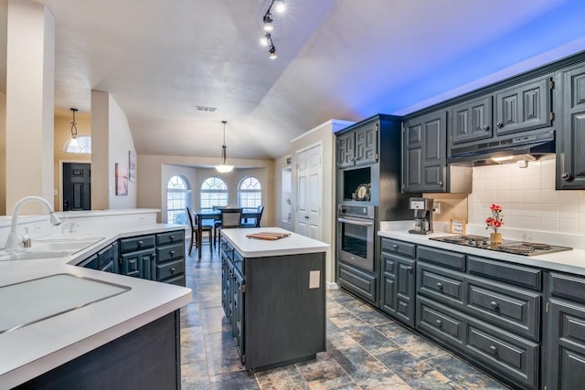kitchen featuring stainless steel oven, a center island, under cabinet range hood, stovetop, and a sink