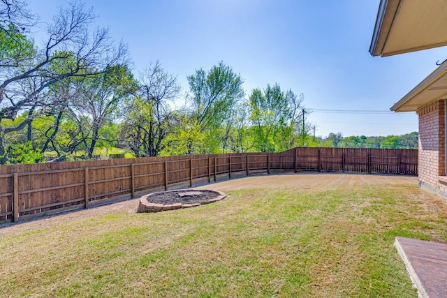 view of yard with a fenced backyard and a fire pit