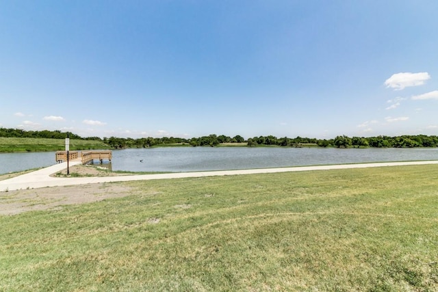 view of dock with a yard and a water view