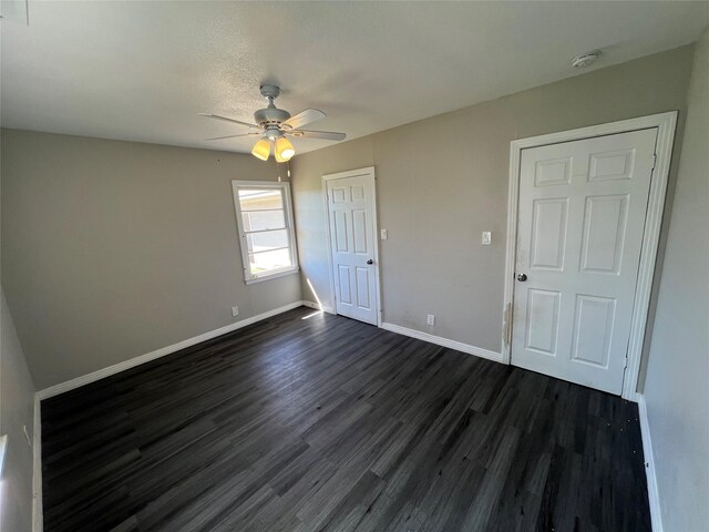 2912 W Elm St, Denison, TX 75020 - unfurnished bedroom featuring dark wood-style flooring, baseboards, and ceiling fan