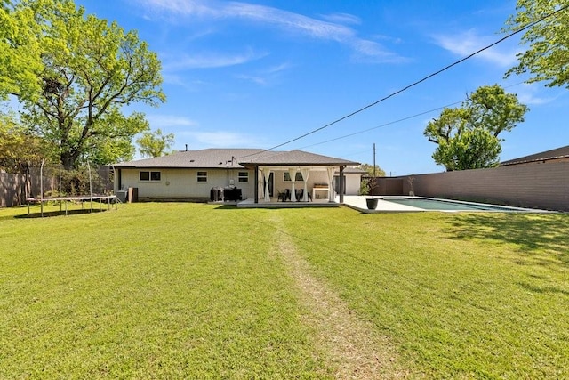 505 Heyser Dr, Dallas, TX 75224 - back of house with a lawn, a fenced backyard, and a trampoline