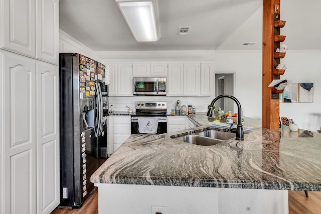 105 Park Trail Pl, Joshua, TX 76058 - kitchen with stainless steel appliances, a sink, a peninsula, white cabinetry, and dark stone counters