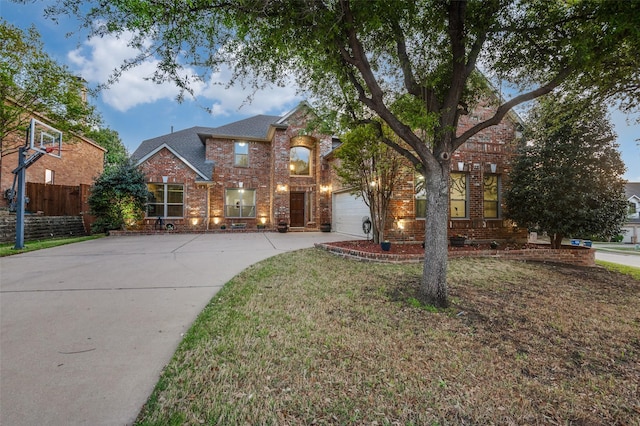 traditional-style house featuring concrete driveway, a front lawn, fence, and brick siding