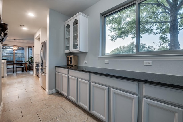 kitchen with glass insert cabinets, recessed lighting, a healthy amount of sunlight, and freestanding refrigerator