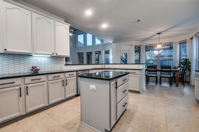 kitchen featuring a peninsula, a center island, stainless steel dishwasher, a sink, and backsplash