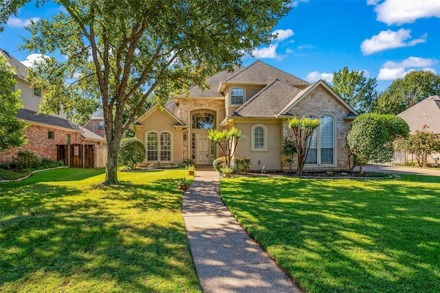 view of front of property featuring fence, stone siding, stucco siding, and a front yard
