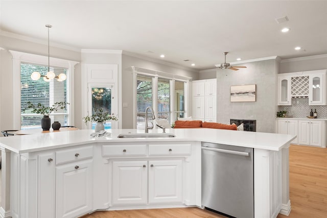 kitchen featuring a fireplace, light wood-style floors, dishwasher, ceiling fan with notable chandelier, and a sink