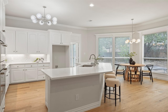 kitchen with a sink, ornamental molding, and an inviting chandelier