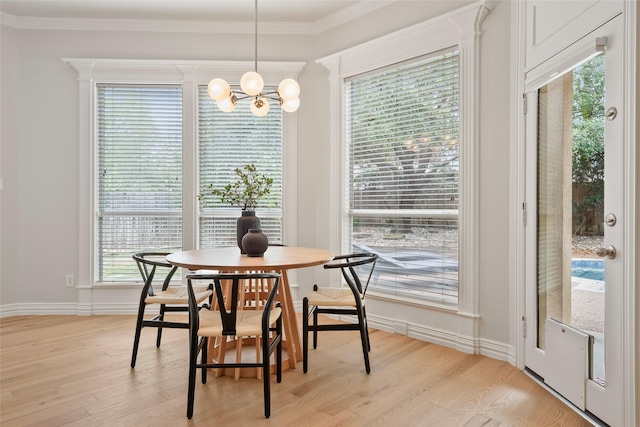 dining room featuring a chandelier, light wood-type flooring, baseboards, and ornamental molding