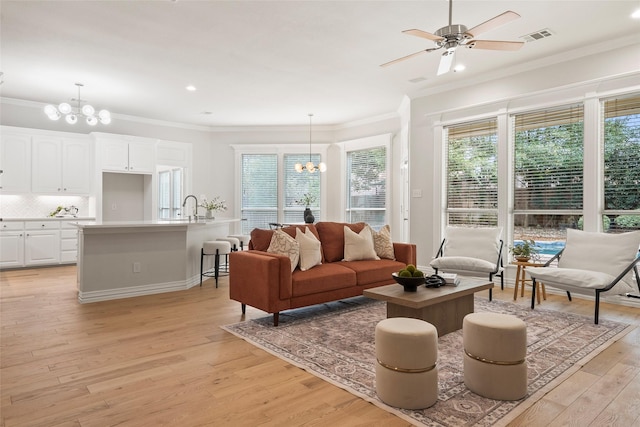 living area with ornamental molding, light wood-type flooring, and ceiling fan with notable chandelier