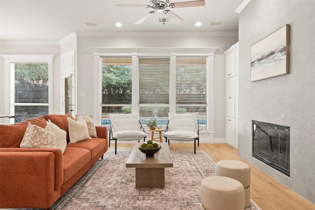 living area with ornamental molding, ceiling fan, light wood-type flooring, a fireplace, and recessed lighting