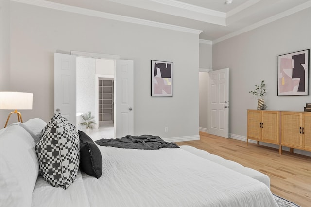 bedroom featuring ornamental molding, baseboards, a tray ceiling, and wood finished floors