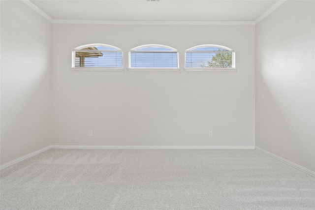 carpeted spare room featuring baseboards, crown molding, and a healthy amount of sunlight