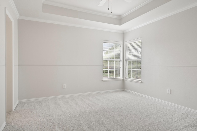 carpeted spare room featuring ornamental molding, ceiling fan, a raised ceiling, and baseboards