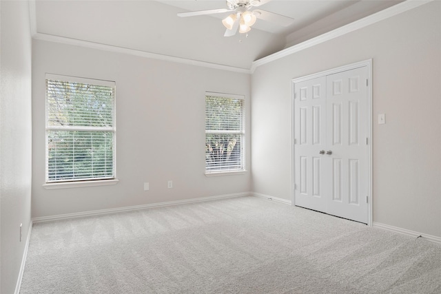 unfurnished bedroom featuring crown molding, carpet flooring, baseboards, and vaulted ceiling