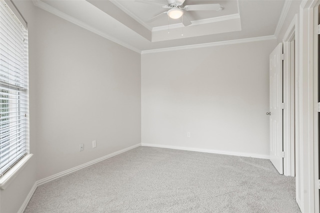 interior space featuring baseboards, crown molding, carpet floors, a tray ceiling, and ceiling fan