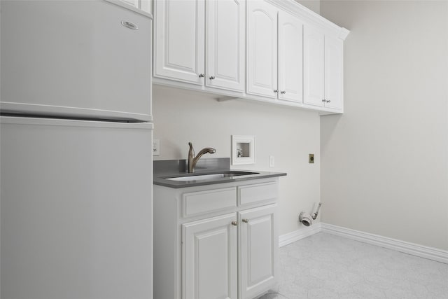 clothes washing area featuring baseboards, electric dryer hookup, washer hookup, cabinet space, and a sink