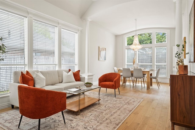 living room featuring light wood-style floors, a healthy amount of sunlight, decorative columns, and vaulted ceiling