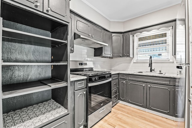 kitchen with stainless steel range with gas stovetop, a sink, tasteful backsplash, under cabinet range hood, and ornamental molding