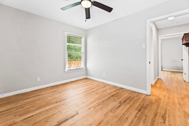 empty room featuring a ceiling fan, baseboards, and light wood-style floors