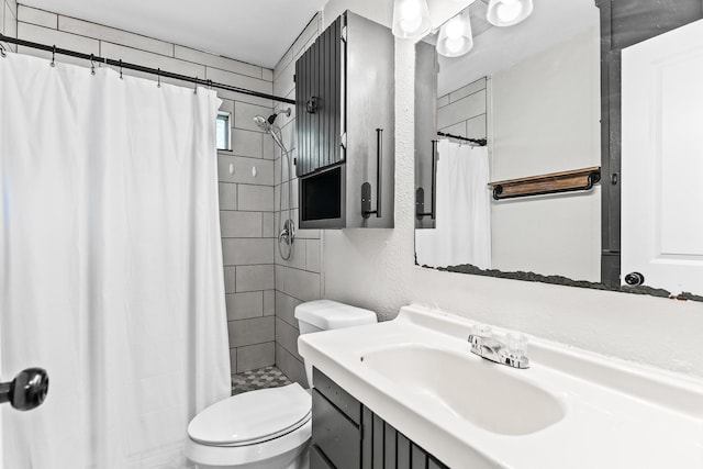 full bath with a tile shower, toilet, a textured wall, and vanity