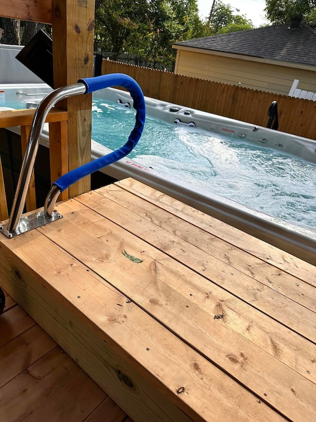view of swimming pool with an outdoor hot tub and fence