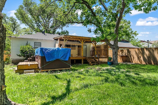 back of house with fence, a yard, a hot tub, and a deck