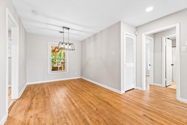 unfurnished dining area featuring light wood-style flooring, baseboards, recessed lighting, and a chandelier