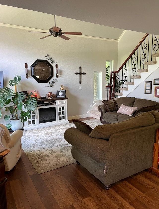 living room featuring wood finished floors, ornamental molding, a ceiling fan, and stairway