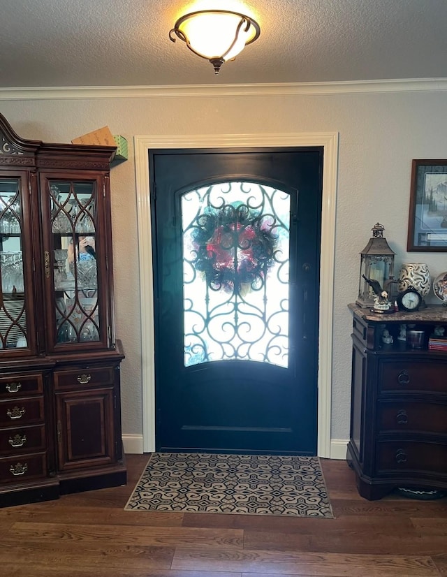 foyer with a textured wall, dark wood-style flooring, a textured ceiling, and ornamental molding