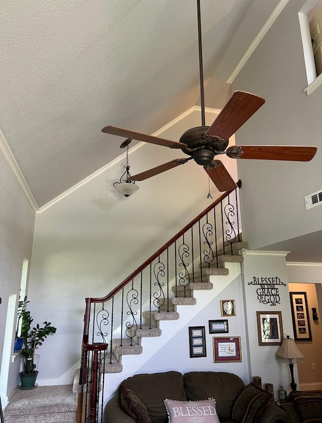 staircase with crown molding, high vaulted ceiling, ceiling fan, a textured ceiling, and visible vents