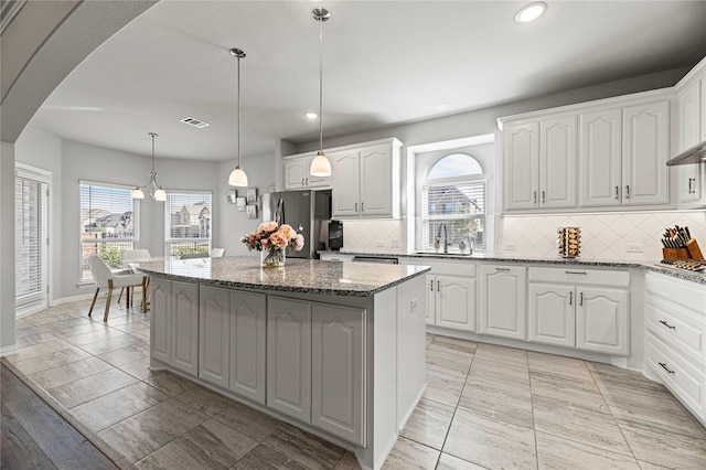 1036 Rutherford St, Frisco, TX 75036 - kitchen featuring light stone countertops, a center island, visible vents, a sink, and appliances with stainless steel finishes