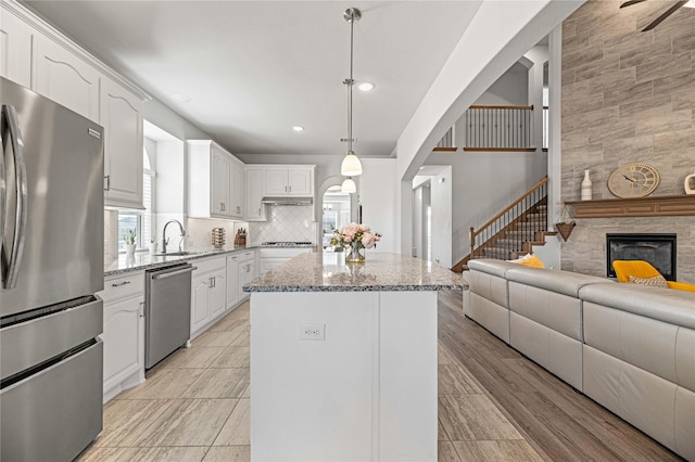 1036 Rutherford St, Frisco, TX 75036 - kitchen featuring open floor plan, a kitchen island, light stone counters, and appliances with stainless steel finishes